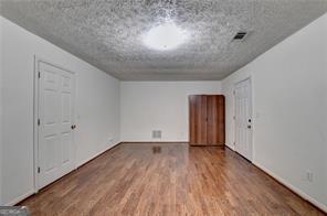 empty room featuring a textured ceiling, visible vents, and wood finished floors