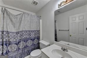 full bathroom with visible vents, a shower with shower curtain, vanity, and toilet