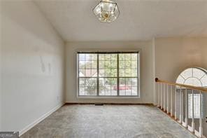 empty room featuring carpet, vaulted ceiling, and baseboards