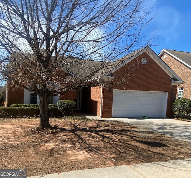 view of front facade with a garage, brick siding, and driveway