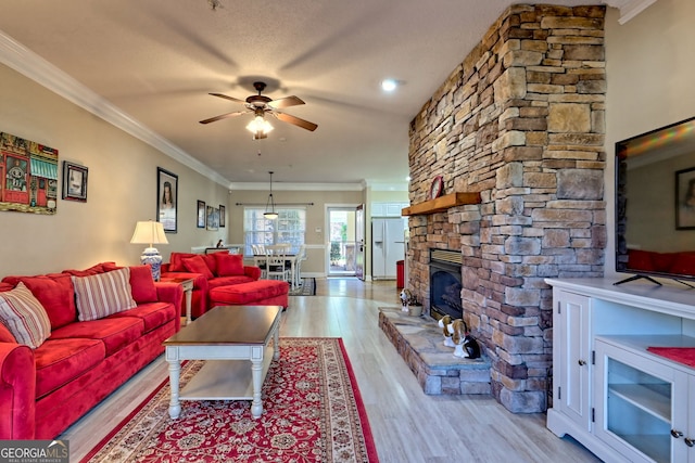 living area with ornamental molding, a fireplace, light wood-style flooring, and a ceiling fan