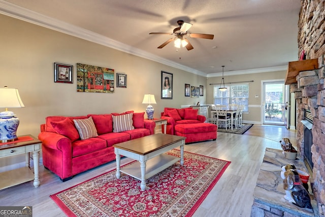 living area featuring ceiling fan, a fireplace, ornamental molding, and wood finished floors