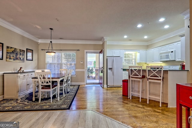 dining room featuring crown molding, baseboards, wood finished floors, and recessed lighting