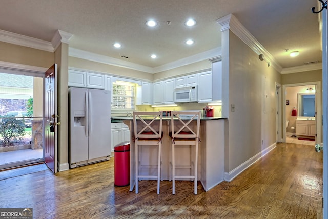 kitchen featuring white appliances, white cabinetry, and wood finished floors