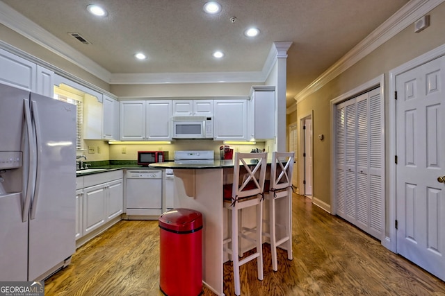 kitchen featuring ornamental molding, white appliances, dark countertops, and white cabinets