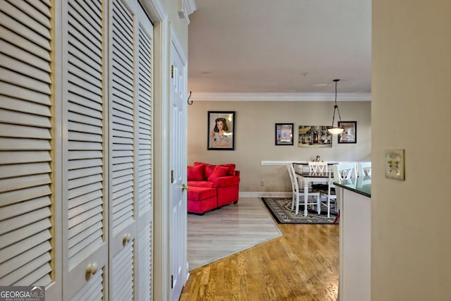 hallway featuring baseboards, wood finished floors, and crown molding