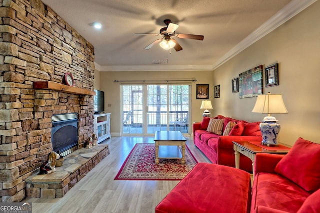 living room featuring a fireplace, crown molding, a ceiling fan, wood finished floors, and baseboards