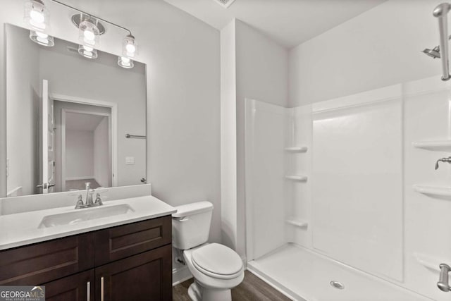 bathroom with toilet, walk in shower, wood finished floors, and vanity