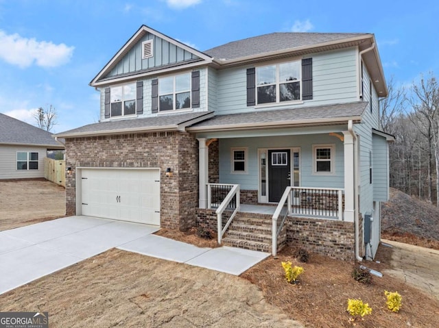 view of front of house with an attached garage, covered porch, brick siding, concrete driveway, and board and batten siding