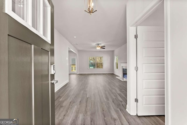 foyer entrance featuring ceiling fan, baseboards, wood finished floors, and a glass covered fireplace