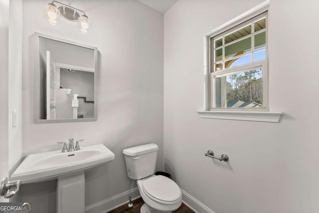 bathroom featuring wood finished floors, a sink, toilet, and baseboards