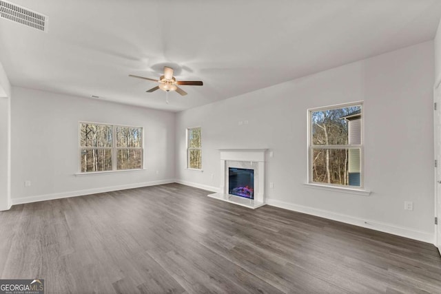 unfurnished living room featuring visible vents, a fireplace, baseboards, and wood finished floors