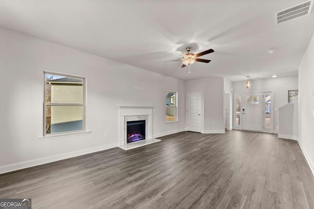 unfurnished living room featuring a fireplace, wood finished floors, visible vents, and baseboards