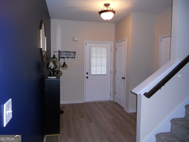 foyer featuring wood finished floors, visible vents, baseboards, and stairs