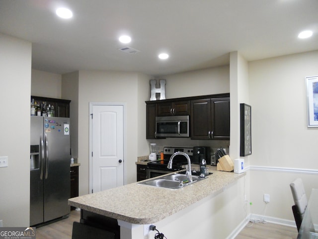 kitchen with stainless steel appliances, recessed lighting, light countertops, light wood-style floors, and a sink