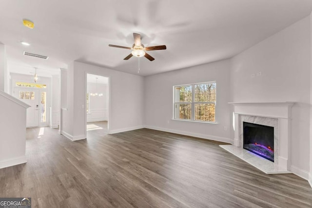 unfurnished living room featuring dark wood-style flooring, a fireplace, visible vents, and baseboards