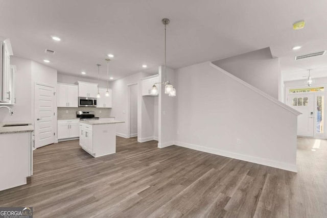 kitchen featuring stainless steel appliances, visible vents, a sink, and wood finished floors