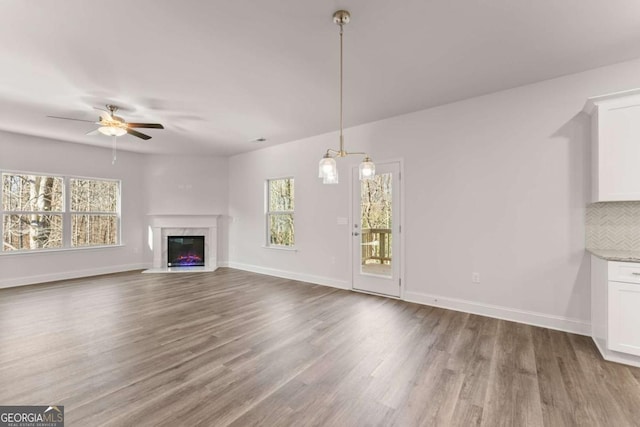 unfurnished living room featuring a premium fireplace, baseboards, and wood finished floors