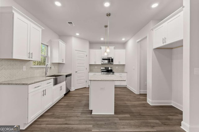 kitchen with a sink, visible vents, white cabinetry, appliances with stainless steel finishes, and a center island