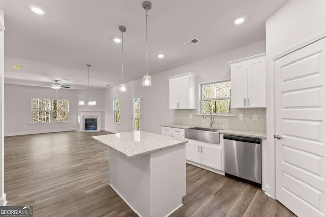 kitchen with a fireplace, a sink, visible vents, stainless steel dishwasher, and decorative backsplash