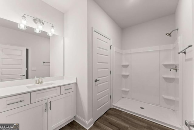 full bathroom featuring walk in shower, vanity, baseboards, and wood finished floors