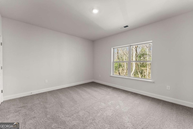 carpeted spare room with visible vents and baseboards