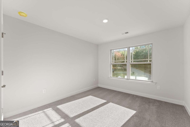 carpeted spare room with visible vents and baseboards