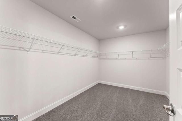 walk in closet featuring visible vents and dark carpet