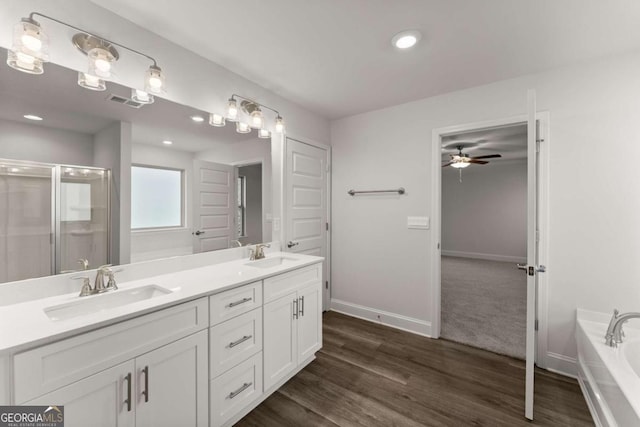 bathroom with double vanity, a stall shower, a sink, and baseboards