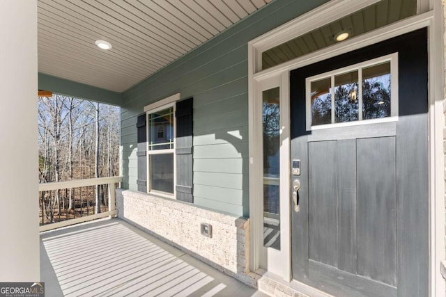 property entrance featuring a porch and brick siding