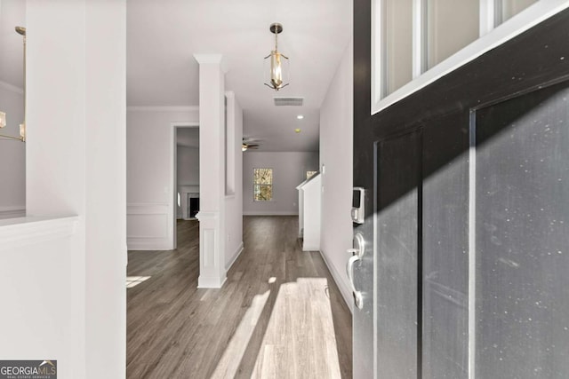 entrance foyer with decorative columns, visible vents, ceiling fan, ornamental molding, and wood finished floors