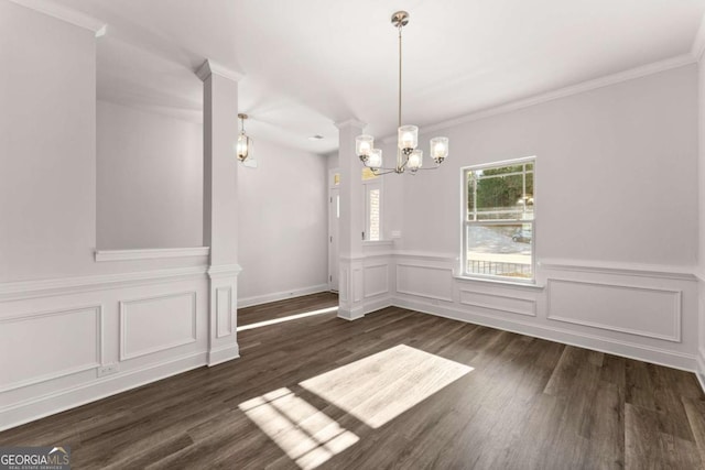 unfurnished dining area with ornamental molding, decorative columns, an inviting chandelier, and wood finished floors