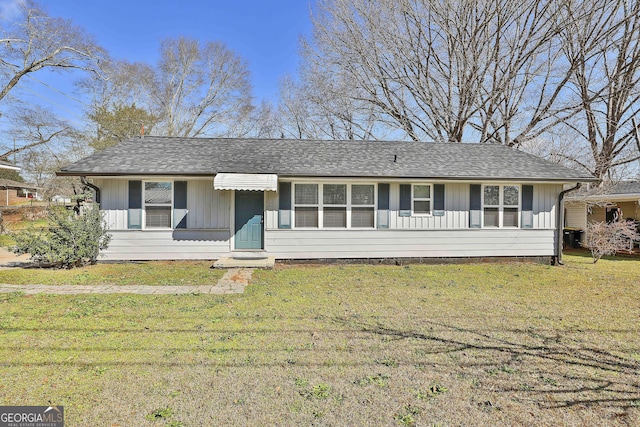 ranch-style home with a front lawn, board and batten siding, and roof with shingles