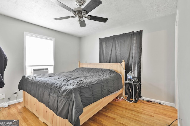 bedroom with ceiling fan, a textured ceiling, wood finished floors, cooling unit, and baseboards