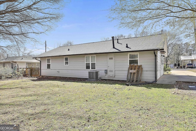 back of house featuring a shingled roof, fence, cooling unit, and a yard