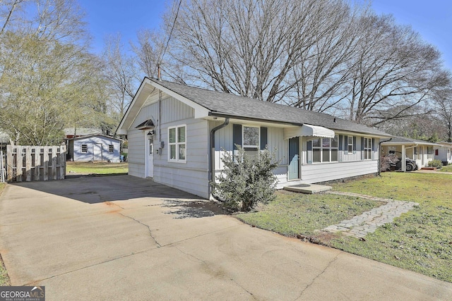 view of front of property featuring driveway, a front lawn, board and batten siding, and roof with shingles