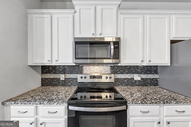 kitchen featuring stainless steel appliances, dark stone countertops, decorative backsplash, and white cabinets