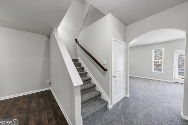 staircase with carpet floors, arched walkways, and baseboards