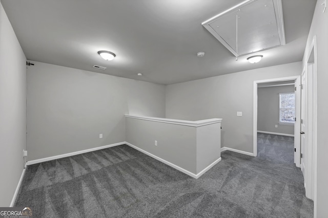 spare room featuring attic access, dark colored carpet, visible vents, and baseboards