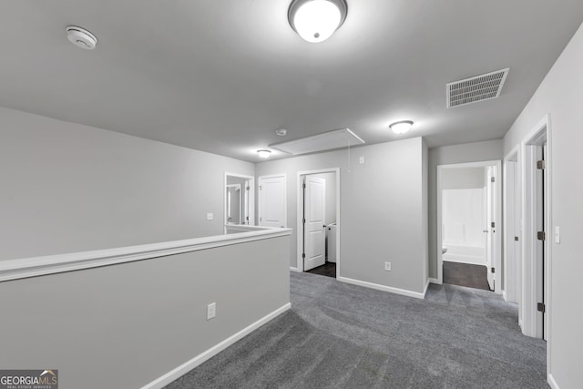 empty room with baseboards, dark colored carpet, visible vents, and attic access