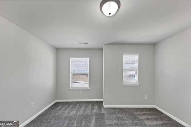 empty room with visible vents, baseboards, and dark colored carpet