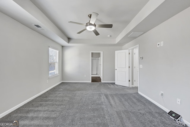 unfurnished bedroom with ceiling fan, carpet floors, visible vents, baseboards, and a tray ceiling