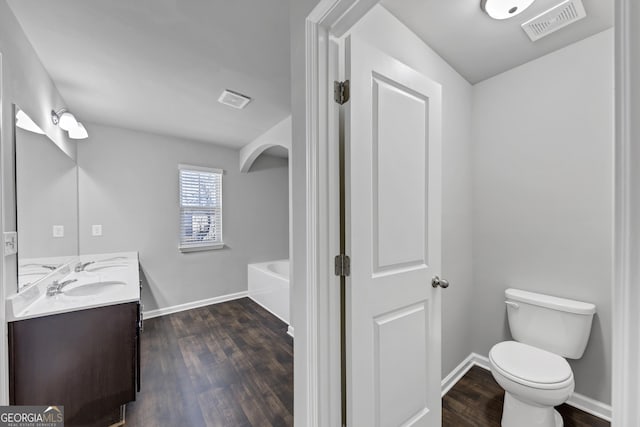 bathroom featuring toilet, visible vents, wood finished floors, and a bath