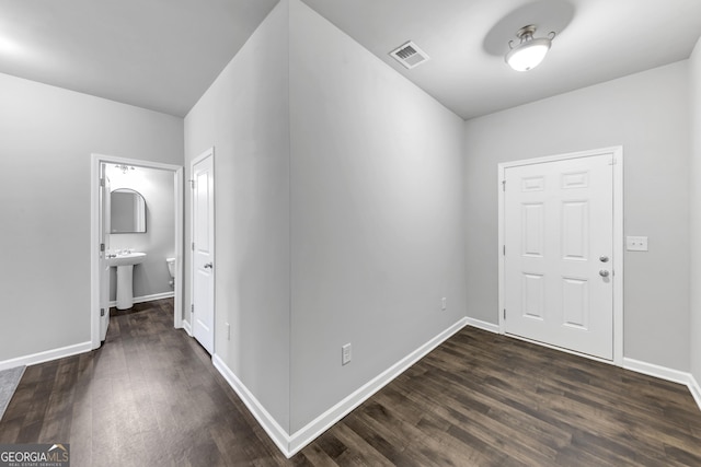 corridor featuring dark wood-type flooring, a sink, visible vents, and baseboards