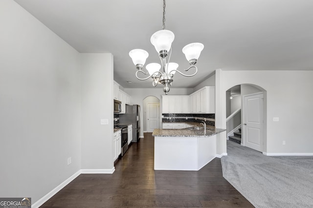 kitchen with arched walkways, appliances with stainless steel finishes, stone counters, and a notable chandelier