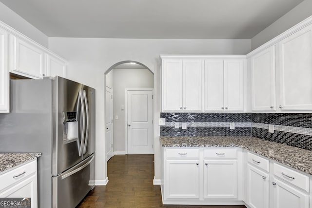 kitchen with stone countertops, white cabinetry, stainless steel refrigerator with ice dispenser, and decorative backsplash