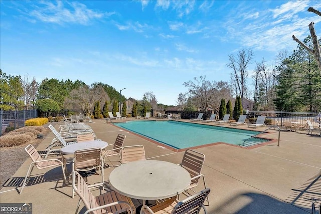 community pool featuring outdoor dining space, a patio area, and fence