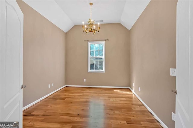 unfurnished room featuring lofted ceiling, light wood-type flooring, an inviting chandelier, and baseboards