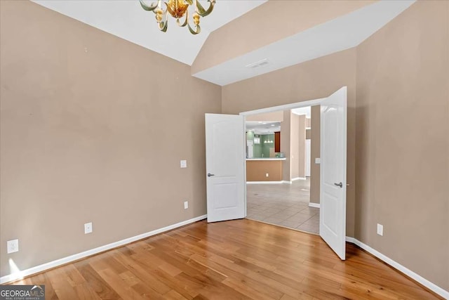 unfurnished bedroom with visible vents, baseboards, lofted ceiling, light wood-style floors, and a notable chandelier