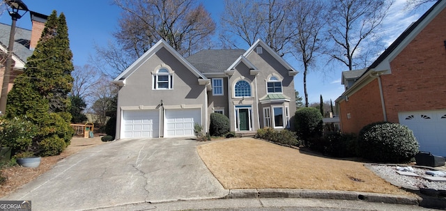 traditional-style house featuring a garage, concrete driveway, and stucco siding